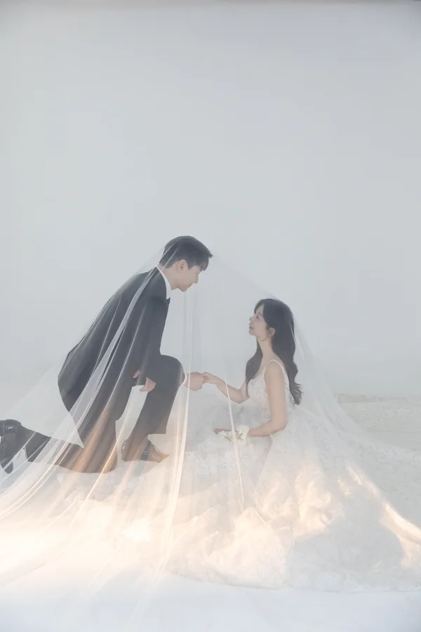 반짝이는 베일 아래에서 손을 잡는 두 사람