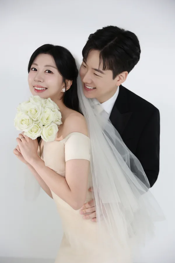 장미 꽃다발을 든 신부를 신랑이 뒤에서 안은 모습