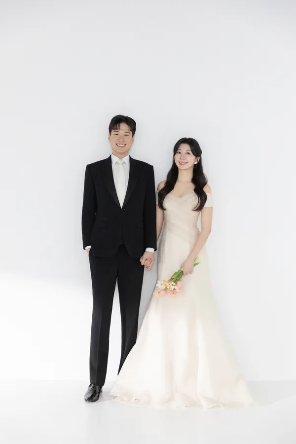 주황빛 꽃다발과 함께 손을 잡고 선 두 사람