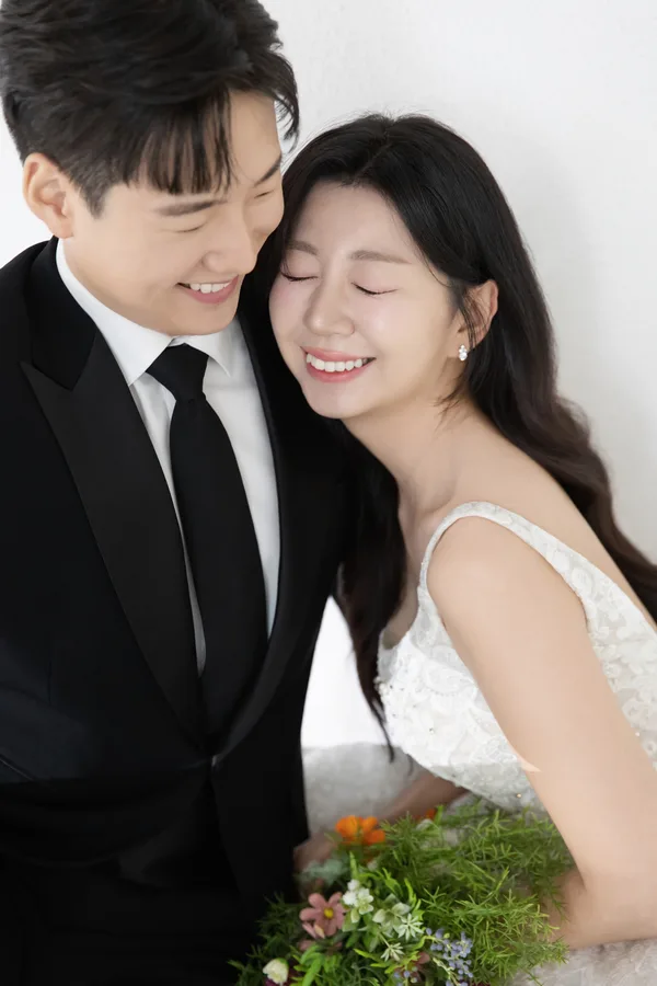 어깨를 맞대고 눈을 감으며 웃는 두 사람