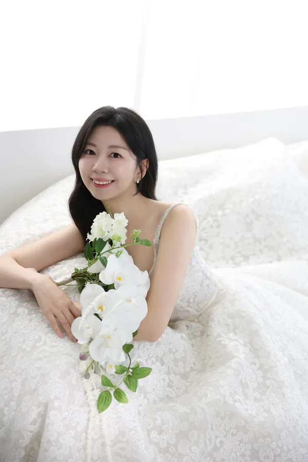 흰 난초 꽃다발을 안고 미소 짓는 신부