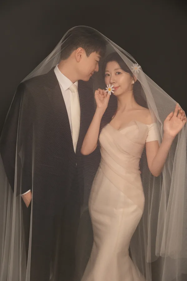 데이지 꽃을 들고 따뜻한 빛의 베일 아래 선 두 사람